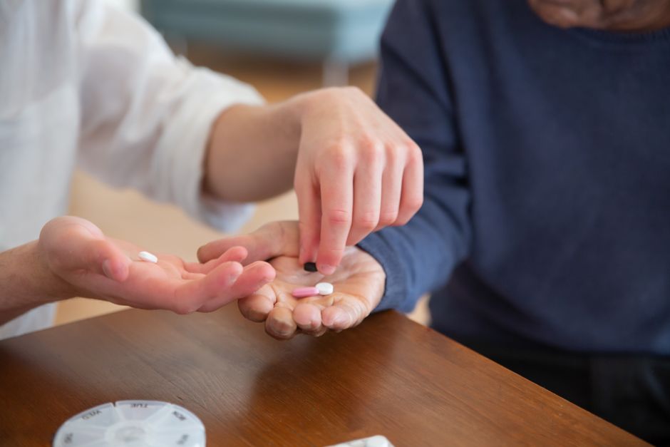 Pessoa entregando comprimidos a outra em um ambiente que sugere discussão sobre medicamentos e saúde.