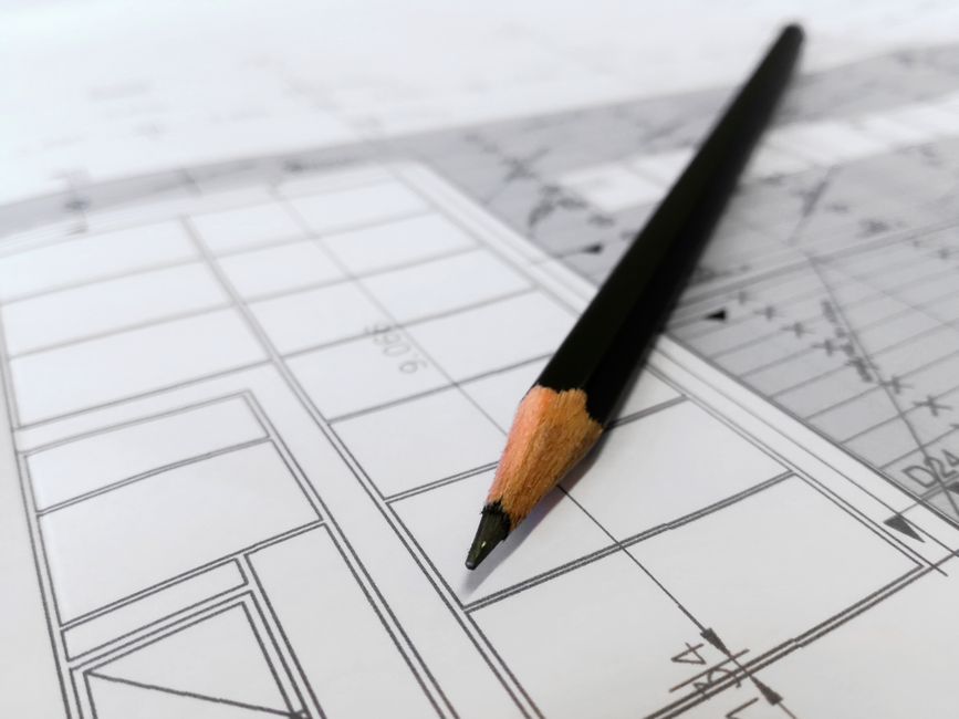 Imagem de um lápis sobre um projeto de arquitetura ou engenharia, simbolizando planejamento e inovação na construção civil.