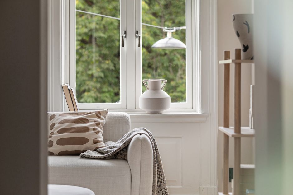 Imagem de um interior aconchegante com uma janela ampla, decoração minimalista e plantas, ideal para ilustrar artigos sobre conforto, decoração ou bem-estar em ambientes internos.