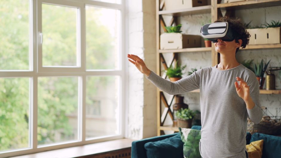 Pessoa interagindo com realidade virtual em ambiente doméstico, explorando tecnologia no contexto de lazer ou inovação.