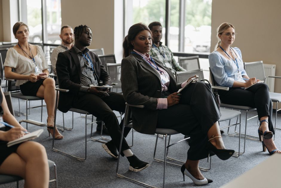 Grupo de pessoas participando de uma palestra ou treinamento empresarial, focando no desenvolvimento profissional e aprendizagem corporativa.