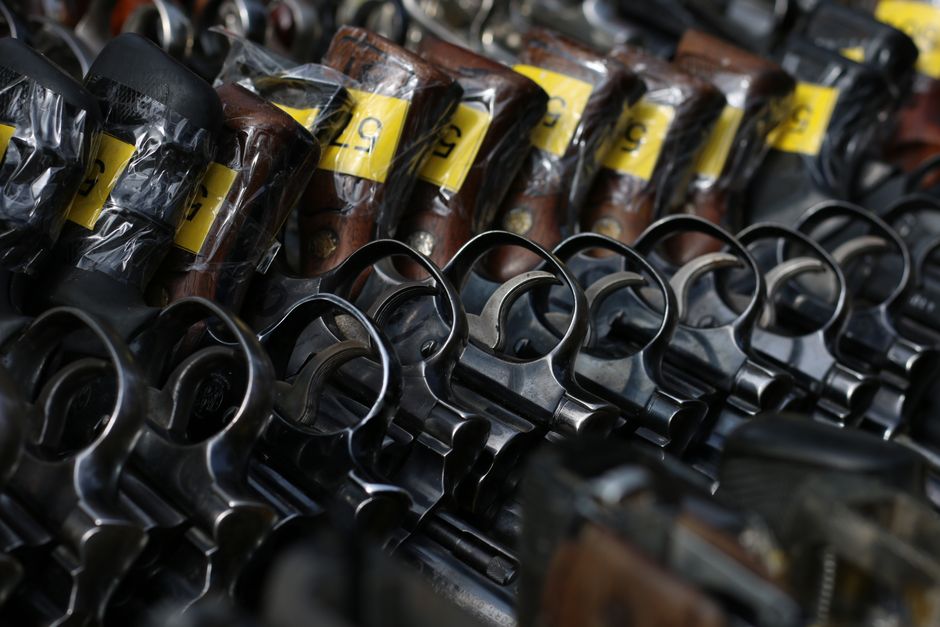 Imagem que mostra uma variedade de itens de armar e armas de fogo alinhadas, sugerindo um tema de segurança, controle de armas ou repressão criminal.