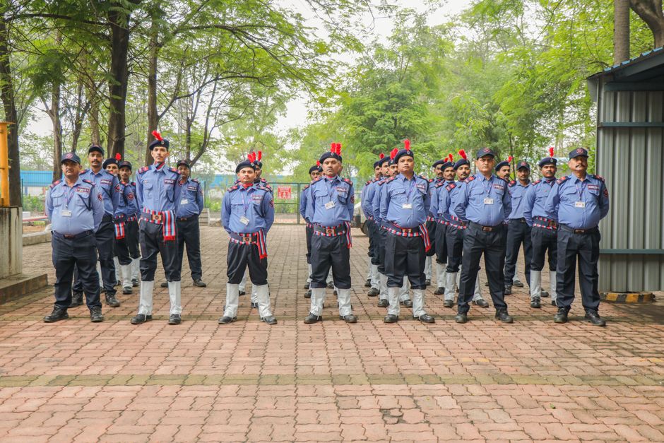 Grupo de policial militar em formação, uniformizados, durante treinamento ao ar livre, com árvores ao fundo.