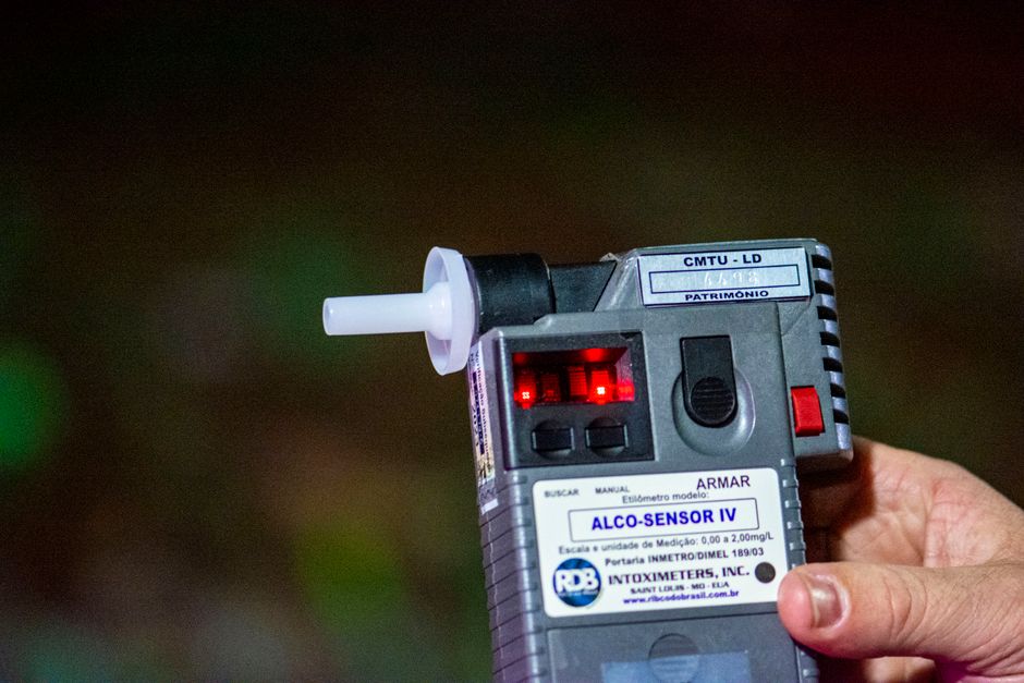 Imagem de um detector de álcool em um procedimento de teste de sobriedade ao ar livre, enfatizando a importância da fiscalização e segurança no trânsito.