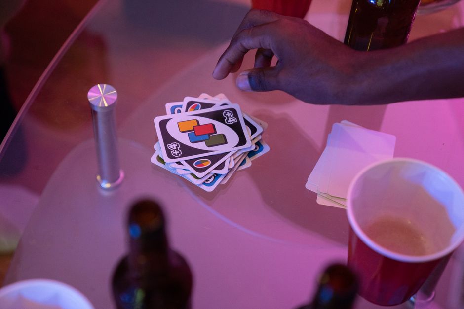 Cena de uma partida de jogo de cartas com um grupo de pessoas, destacando a diversão e interação social em um ambiente descontraído.