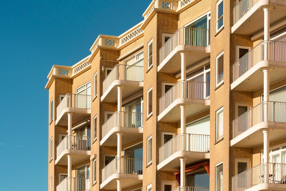 Imagem de um prédio de apartamentos de alta elevação sob céu claro, representando moradia urbana e vida em edifícios residenciais.
