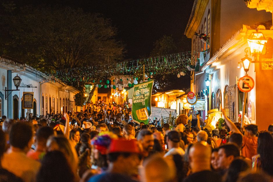 Rua movimentada durante festa tradicional à noite com decoração festiva e grande presença de pessoas.