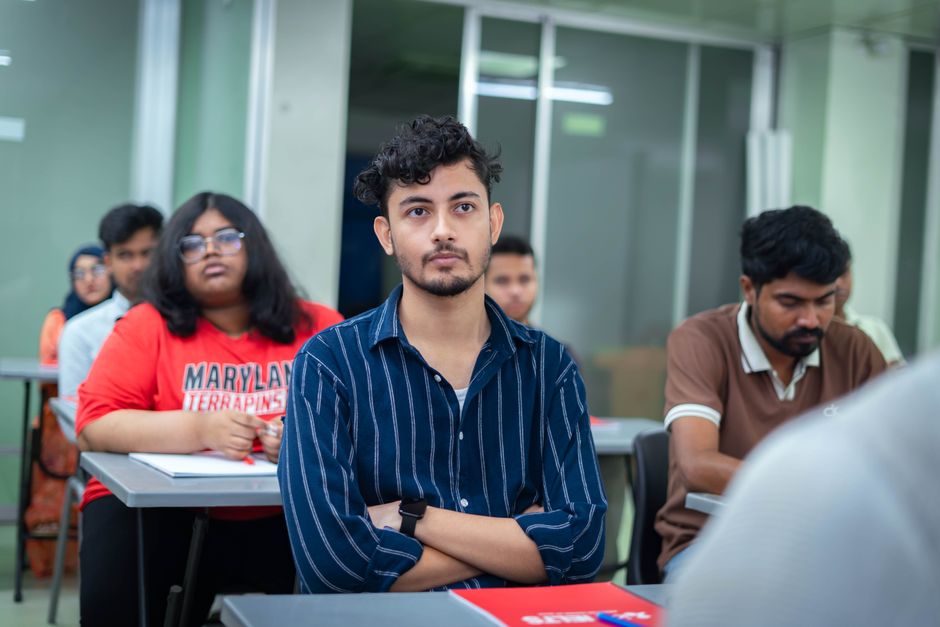 Grupo de estudantes atentos em sala de aula, participando de uma aula ou palestra em ambiente acadêmico.