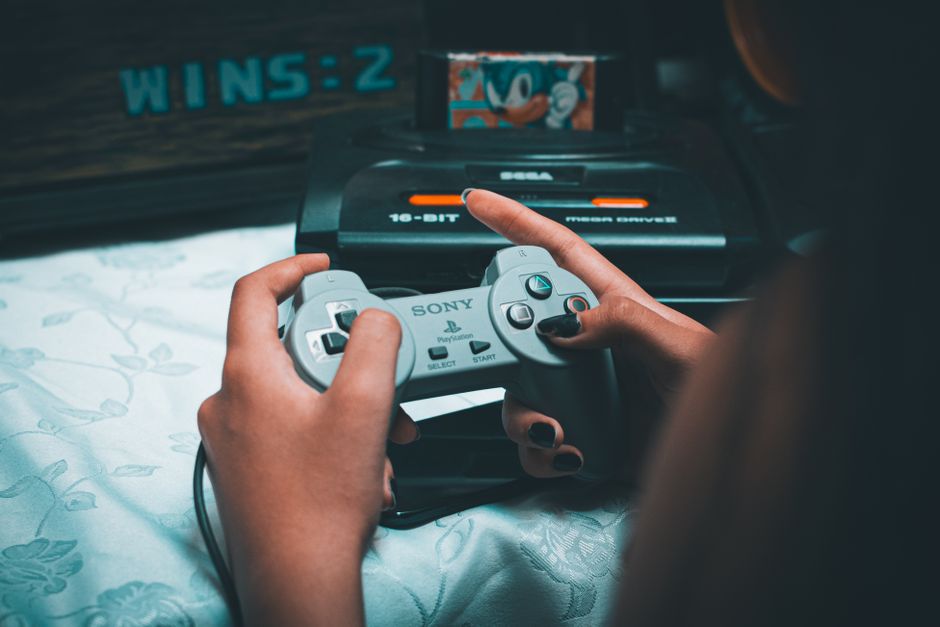 Pessoa jogando videogame com um controle PlayStation, focada na diversão e entretenimento digital.