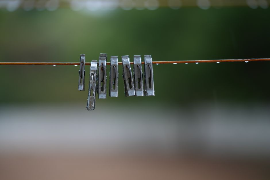 Grampo de roupa preso na linha de varal durante um dia chuvoso, simbolizando organização e cuidados no cotidiano.