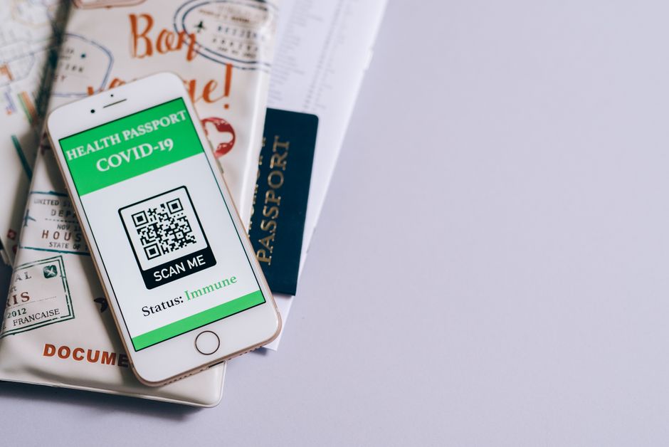 Imagem de um smartphone exibindo um passaporte de vacinação COVID-19, sobre documentos de viagem, simbolizando a importância de requisitos de saúde e viagens internacionais.