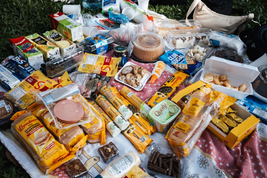 Mesa com variedade de alimentos industrializados e sobremesas, representando o consumo excessivo de produtos processados.