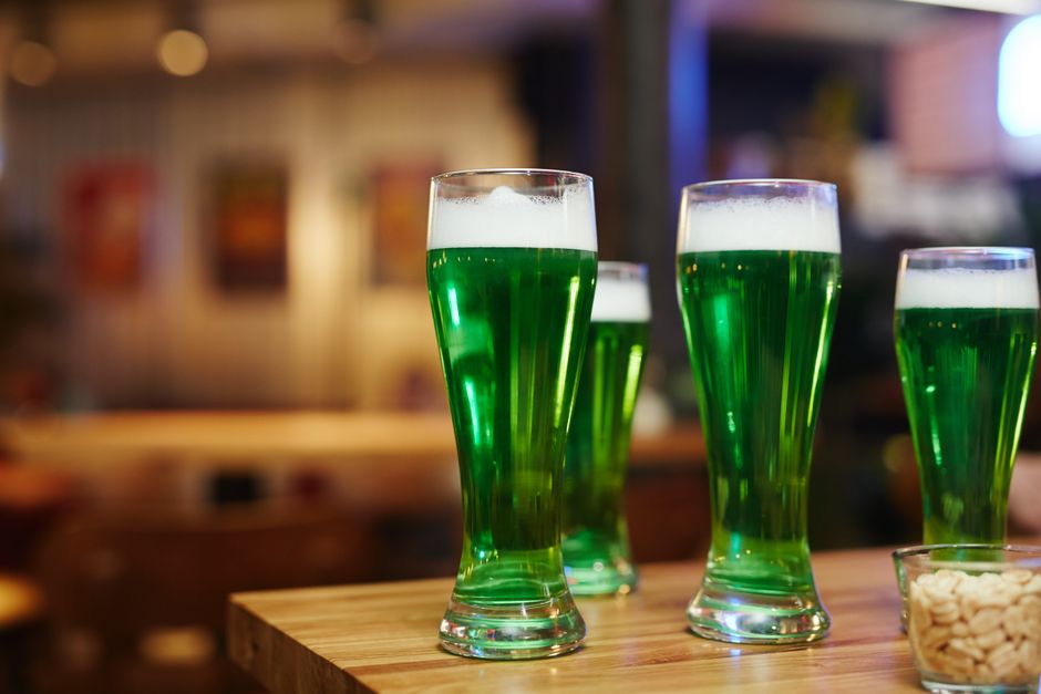 Copo com bebida verde brilhante em um ambiente social, ideal para ilustrar festas ou momentos de descontração.