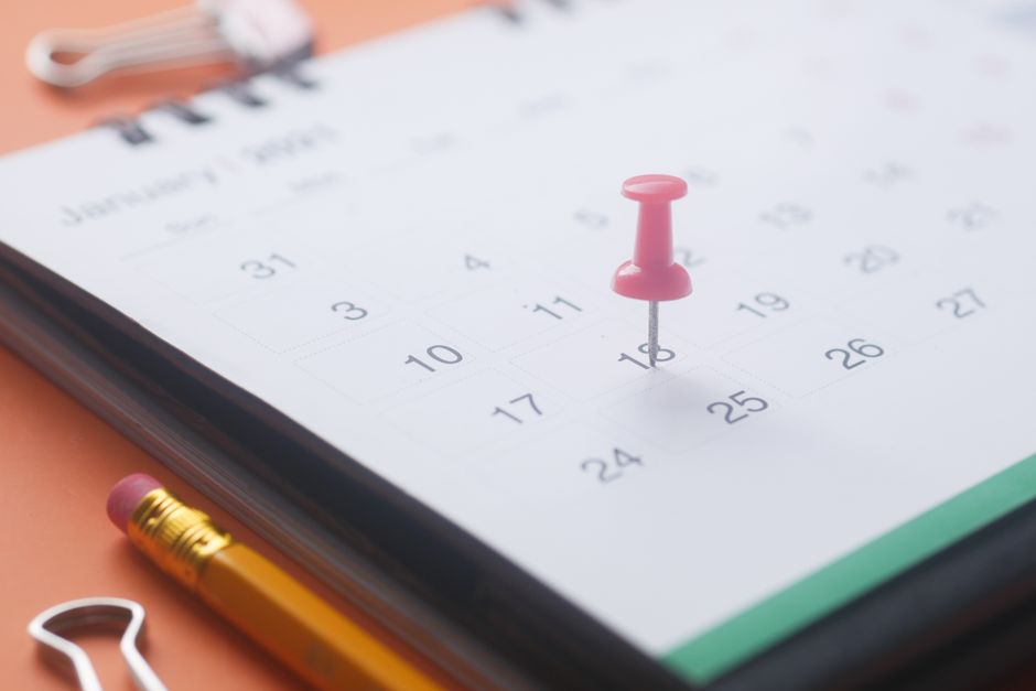 Imagem de um calendário com uma alfineta rosa marcando uma data importante, simbolizando organização e planejamento de compromissos ou eventos.