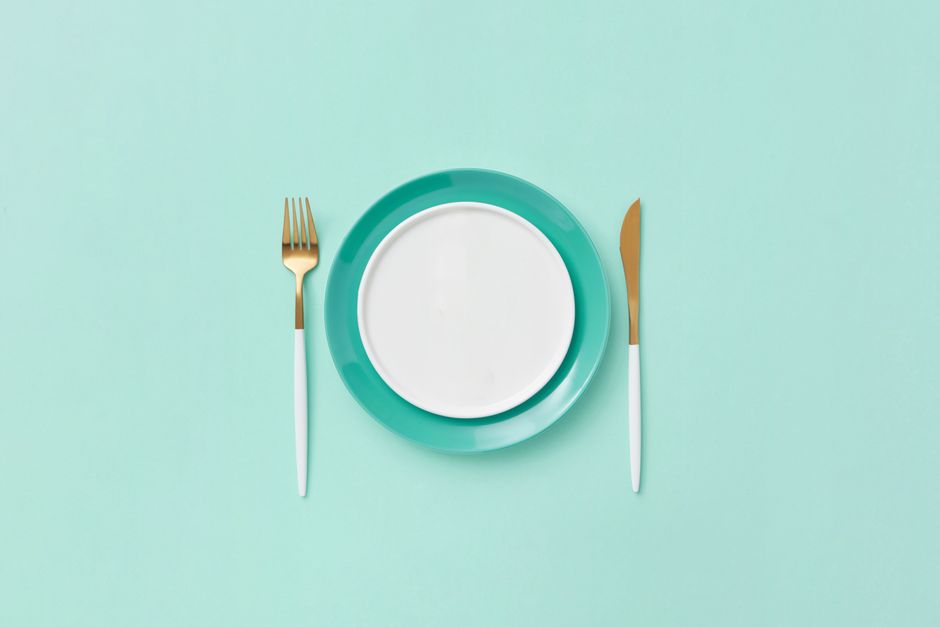 Imagem minimalista de um prato vazio acompanhado de talheres elegantes, ideal para ilustrar temas sobre alimentação, dieta ou estilo de vida saudável.