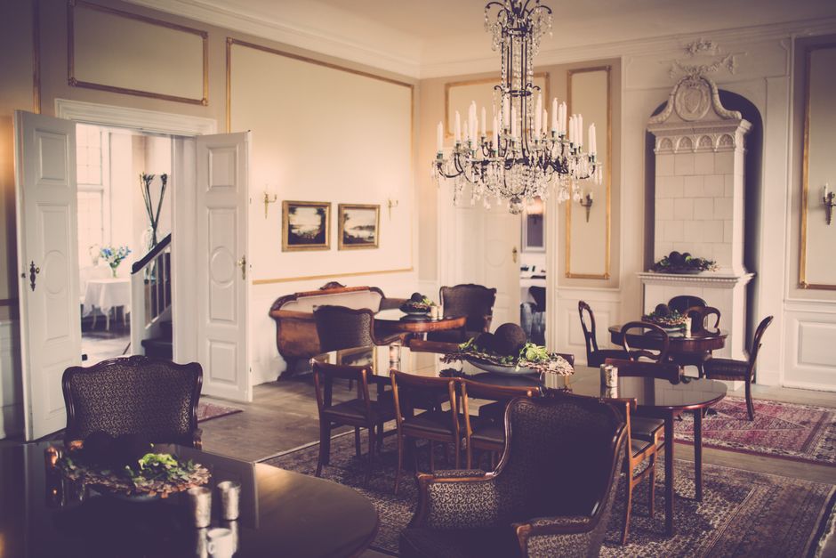 Salão de jantar elegante e sofisticado com decoração clássica, iluminação de chandelier e móveis históricos, ideal para artigos sobre decoração de interiores ou eventos de luxo.