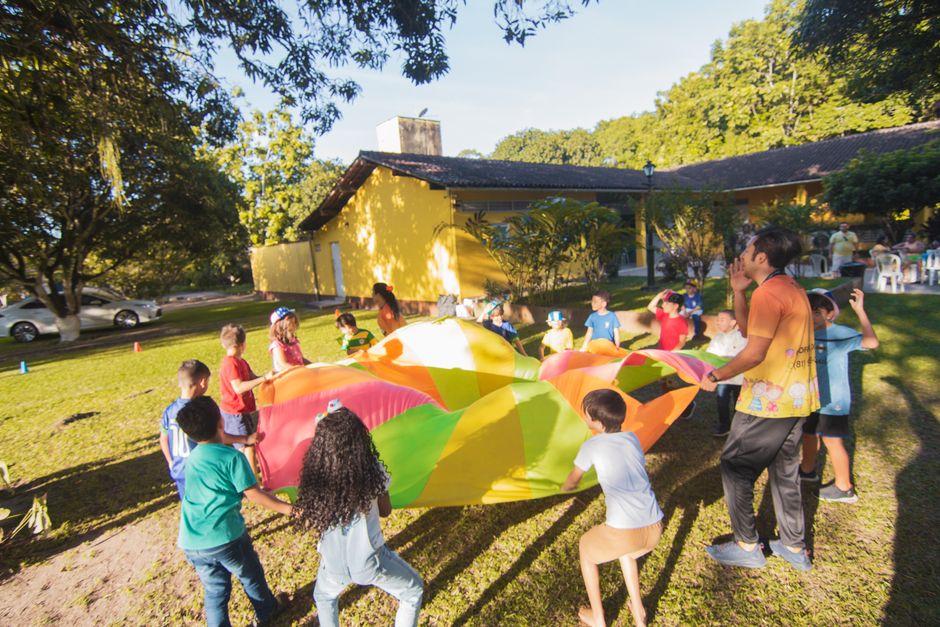 Crianças brincando com um brinquedo de corda colorido ao ar livre durante uma celebração em espaço externo