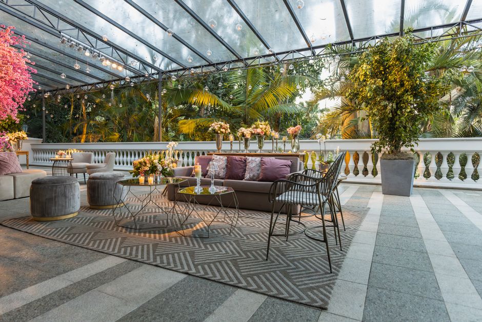 Espaço de convivência ao ar livre decorado com plantas, móveis confortáveis e iluminação suave, ideal para eventos ou momentos de lazer.