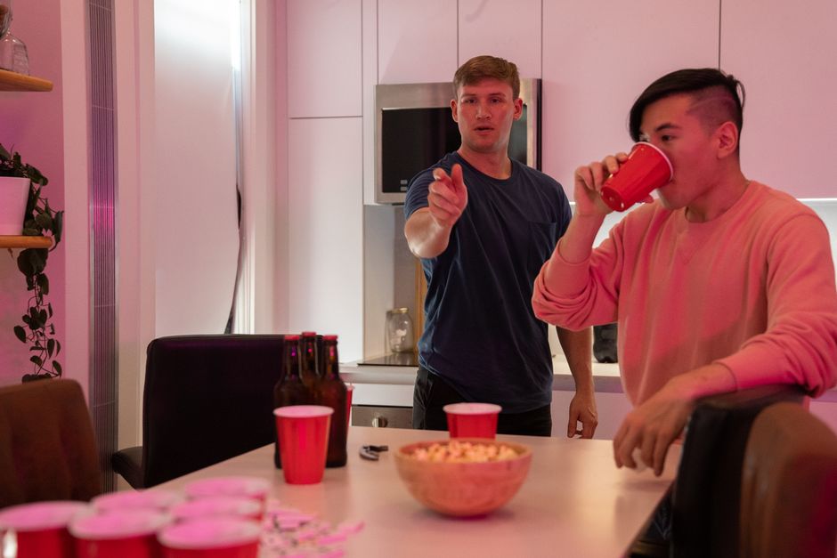 Duas pessoas conversando em uma comemoração ou reunião social em um ambiente moderno de cozinha com iluminação suave.