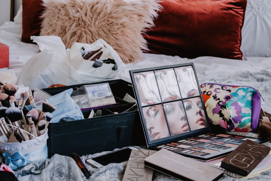 Canto de maquiagem e beleza com produtos organizados sobre a cama, ideal para um blog sobre rotina de cuidados pessoais ou dicas de maquiagem.