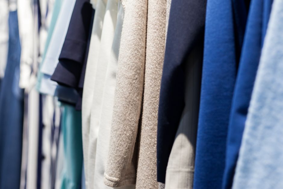 Imagem de cabides com roupas de diferentes cores e tecidos, ideal para ilustrar dicas de moda, tendências ou organização de guarda-roupa.