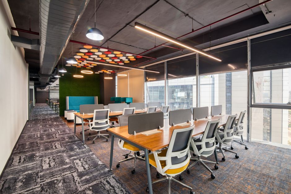 Espaço de coworking moderno e bem iluminado com mesas de trabalho, ideal para ambientes de inovação e colaboração empresarial.