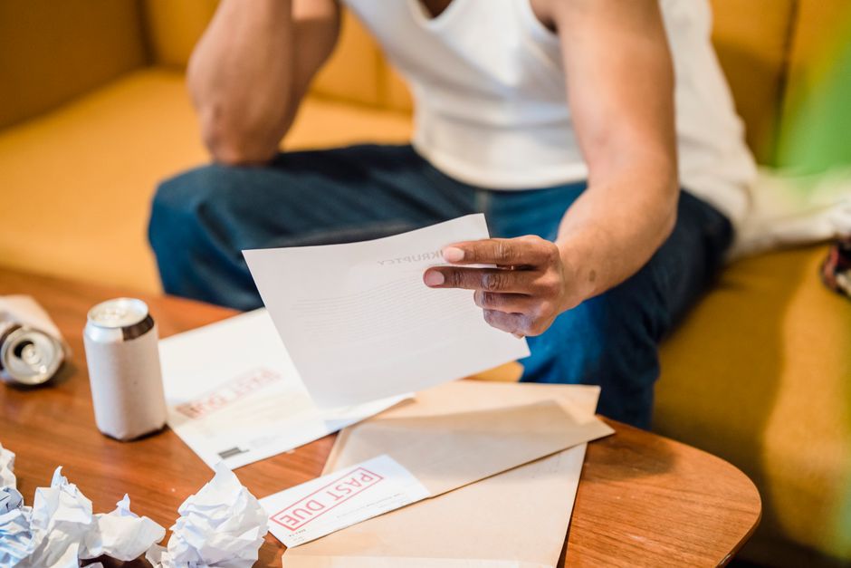 Homem revisando documentos importantes relacionados a finanças ou trabalho, em um ambiente doméstico ou informal.