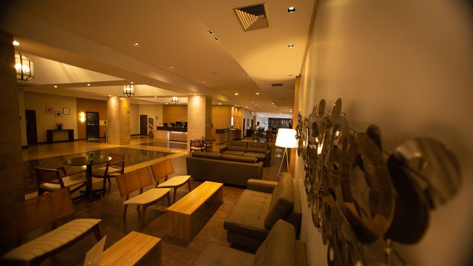 Imagem de um saguão de hotel ou espaço de recepção bem decorado com iluminação suave e ambiente acolhedor.