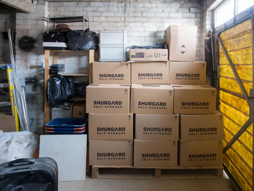 Imagem de um espaço de armazenamento com caixas empilhadas e itens diversos, mostrando organização de materiais.
