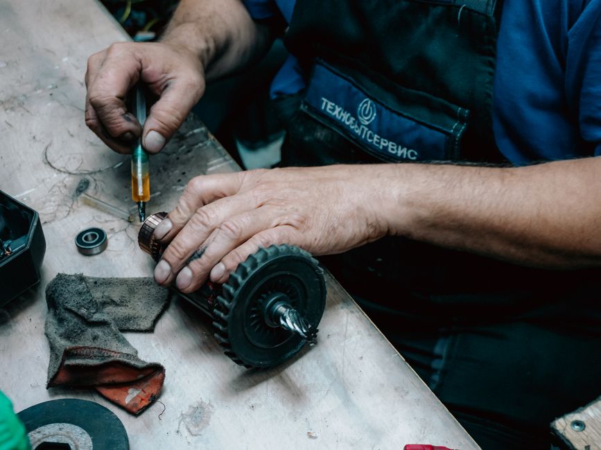 Homem realizando manutenção em equipamento técnico em ambiente de oficina industrial.