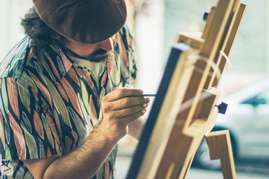 Homem pintando em um estúdio ao ar livre, explorando arte e criatividade.