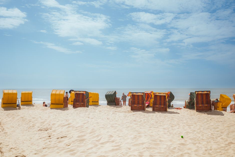 Praia com cadeiras de praia voltadas para o mar, ideal para artigos sobre lazer, férias ou descanso na praia.