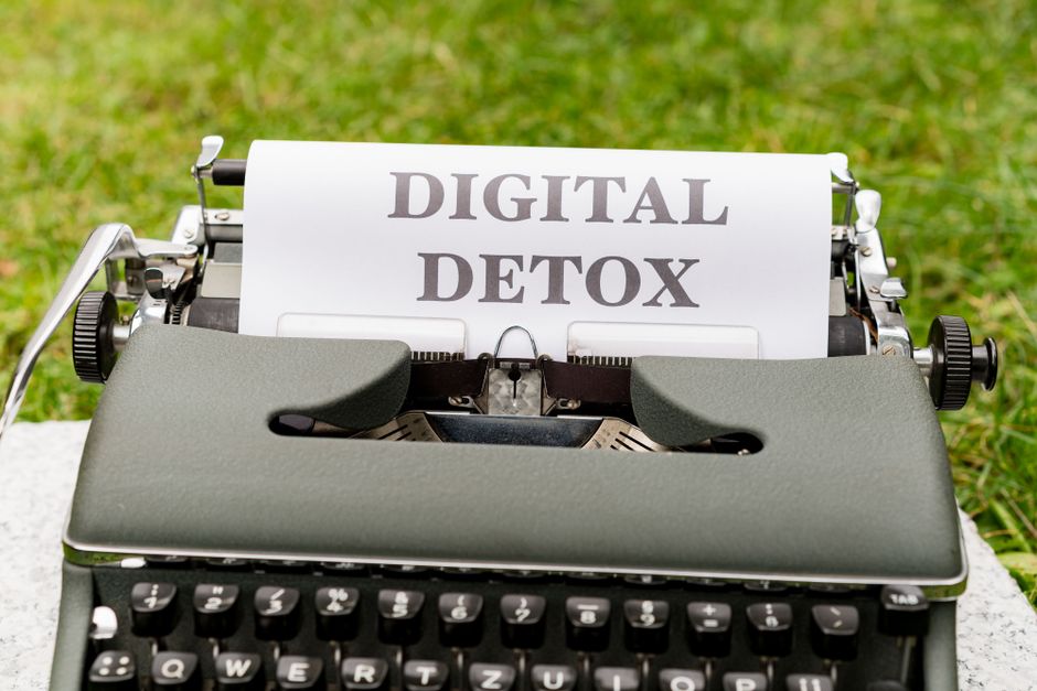 Máquina de escrever com uma folha de papel exibindo a frase 'Digital Detox', simbolizando a desconexão digital e o afastamento de tecnologia.