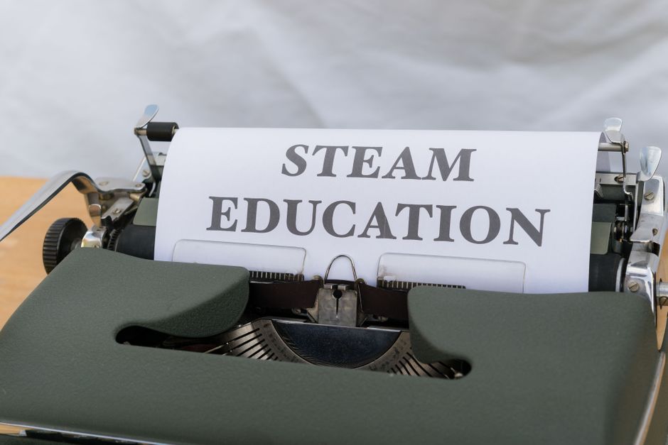 Máquina de escrever vintage com uma folha de papel exibindo a frase 'STEAM EDUCATION', simbolizando a importância da educação STEAM para inovação e desenvolvimento.