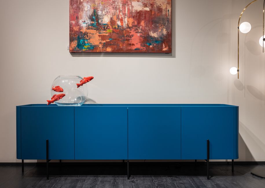 Imagem de um ambiente moderno com um móvel azul, uma pintura abstrata e uma iluminação contemporânea, transmitindo estilo e elegância para decoração de interiores.