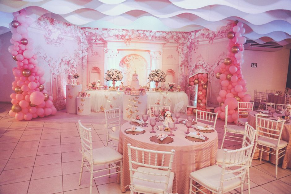 Sala decorada para festa infantil, com tema delicado e elementos em tons de rosa e dourado, ideal para comemoração de aniversário de menina.