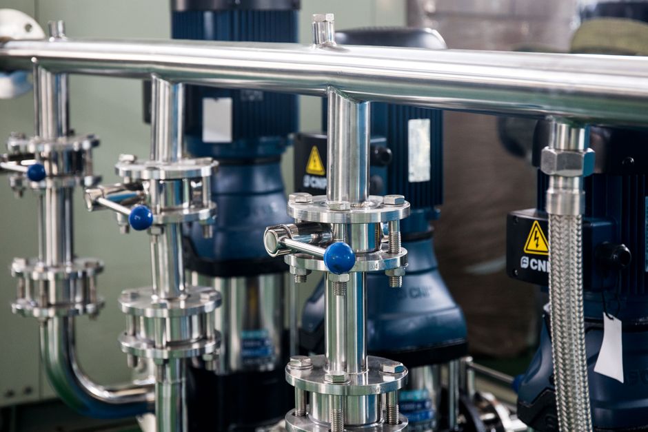 Imagem de uma instalação industrial com componentes metálicos e máquinas de alta tecnologia, representando processos de manufatura e automação.