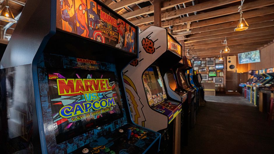 Imagem de uma sala de arcade com várias máquinas de jogos clássicos e retrô, criando um ambiente divertido e nostálgico.