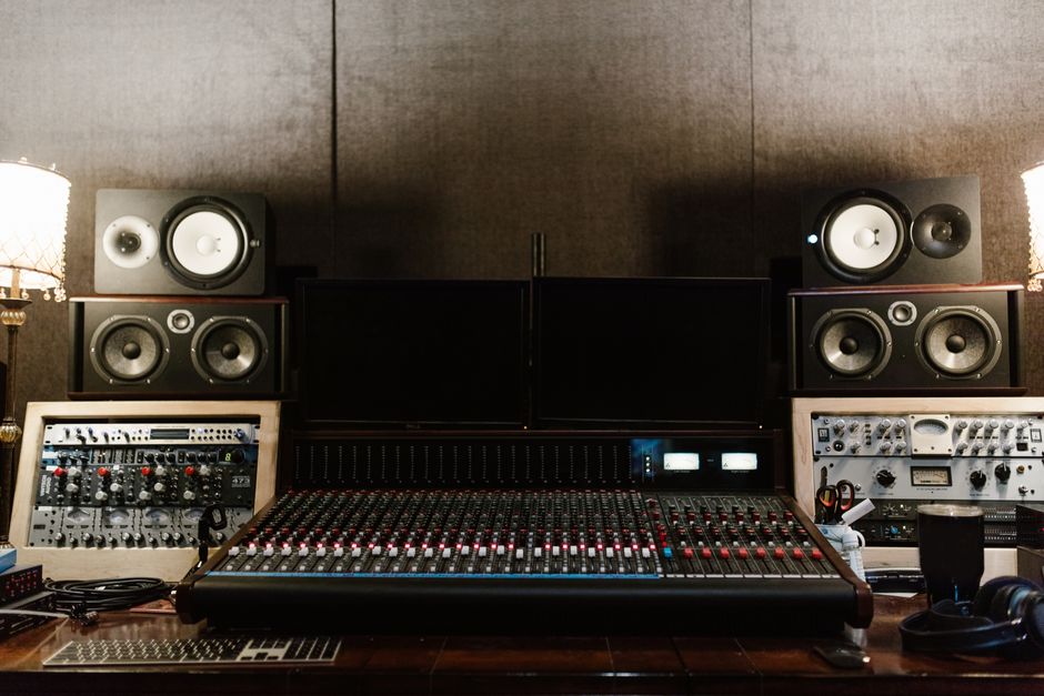 Estúdio de gravação musical equipado com mesa de som, monitores e equipamentos de áudio, adequado para produção musical e mixagem.