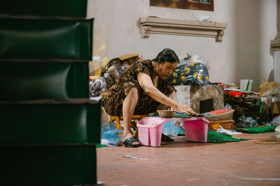 Mulher organizando ou limpando produtos em um ambiente doméstico ou comercial com várias caixas e embalagens ao redor.