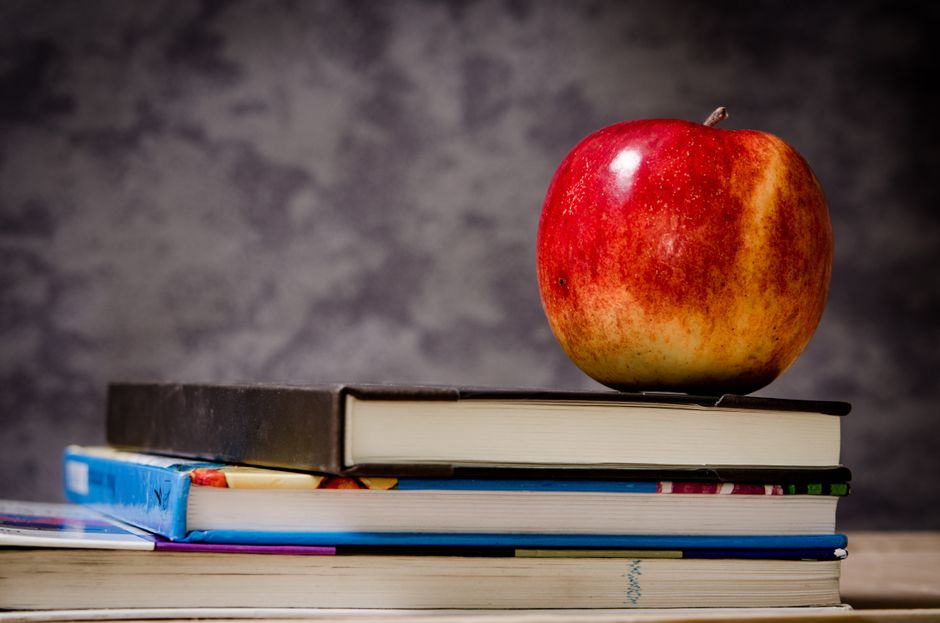 Maçã vermelha sobre uma pilha de livros, simbolizando conhecimento e aprendizado.