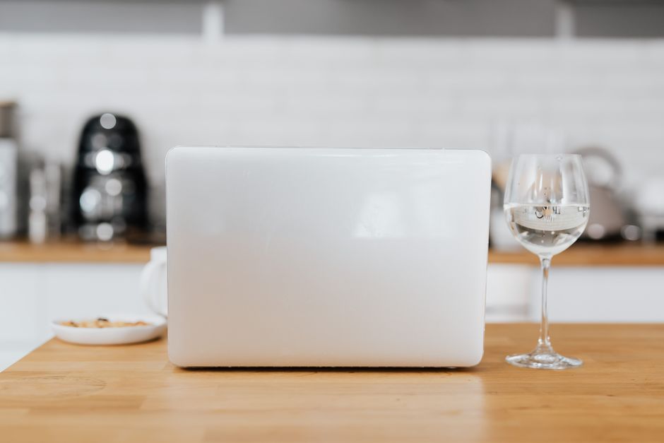 Imagem de uma mesa de cozinha com um laptop fechado, um copo de água e uma tigela, transmitindo um ambiente de trabalho remoto ou estudo em home office.