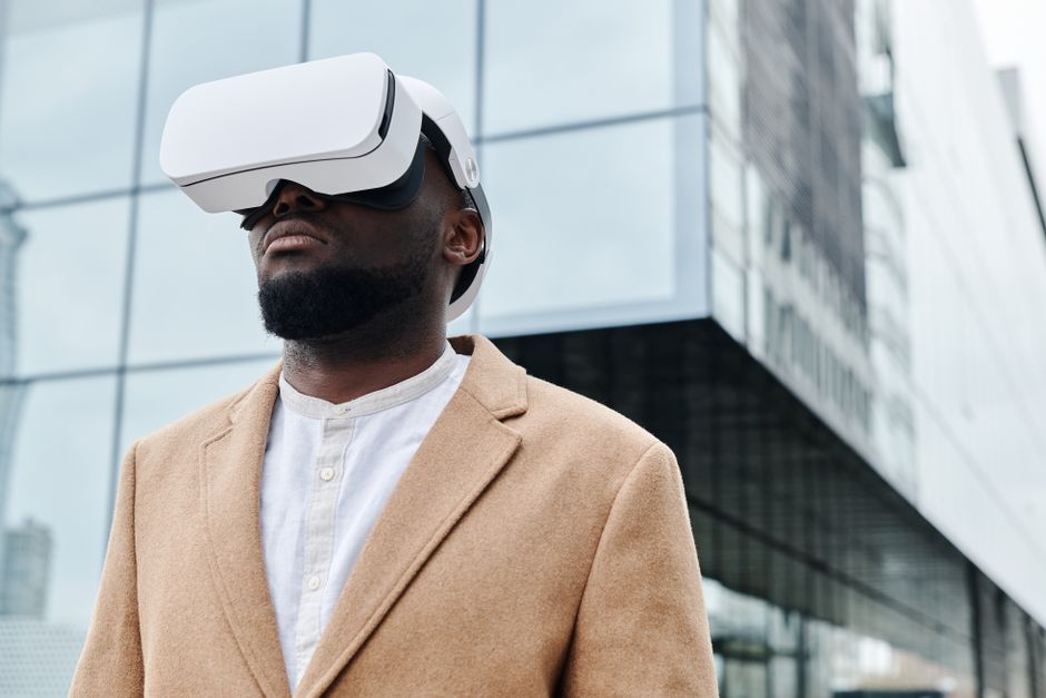 Homem usando óculos de realidade virtual em ambiente urbano, simbolizando inovação tecnológica e o futuro digital.