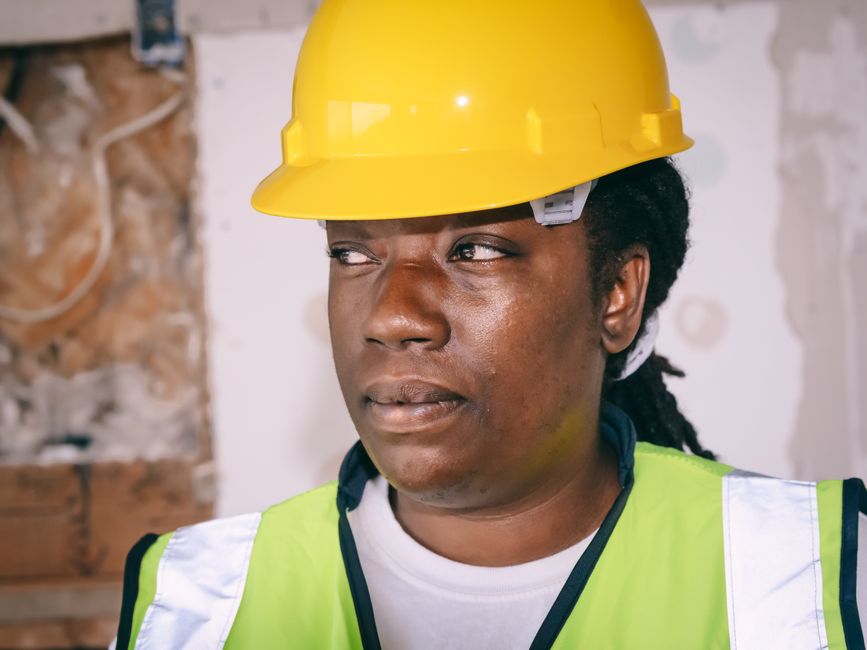 Mulher engenheira ou projetista avaliando uma obra, destacando a importância da segurança e do planejamento na construção civil.