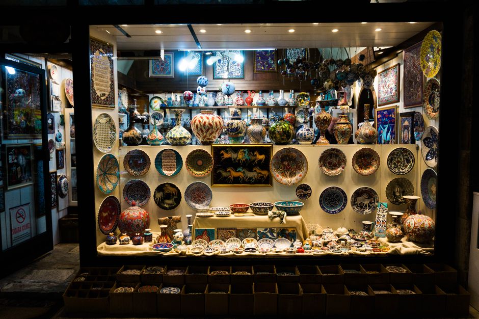 Vitrine de loja de artesanato exibindo cerâmicas e objetos decorativos coloridos e detalhados, ideal para quem aprecia artes manuais e decoração artística.