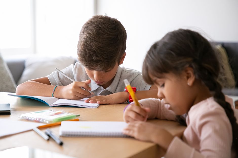 Crianças estudando concentradas, ilustrando a importância do aprendizado e desenvolvimento infantil em ambientes domésticos.