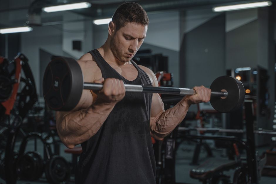Homem treinando força muscular com halteres em academia, evidenciando dedicação ao fitness e saúde.