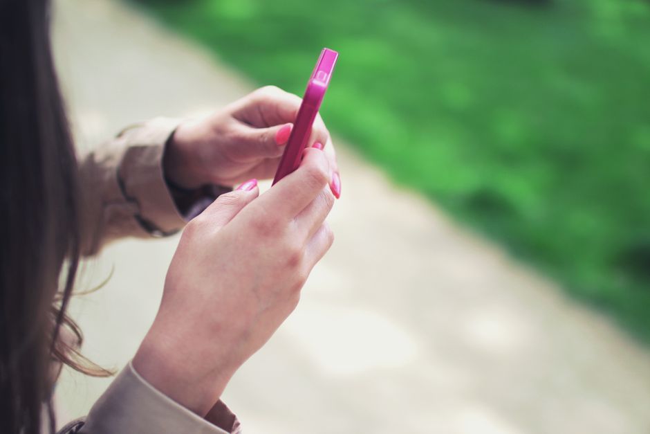 Mulher usando smartphone ao ar livre, representando comunicação e convivência digital.