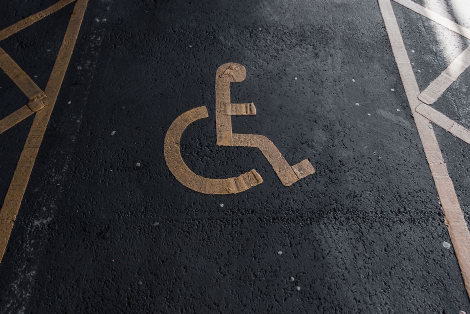 Sinalização de vaga de estacionamento para pessoas com deficiência em uma marcação no chão de um estacionamento.